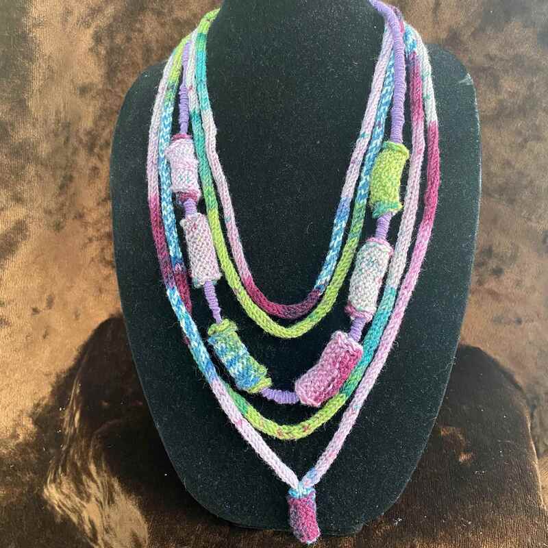 colourful hand knitted necklace displayed on a stand