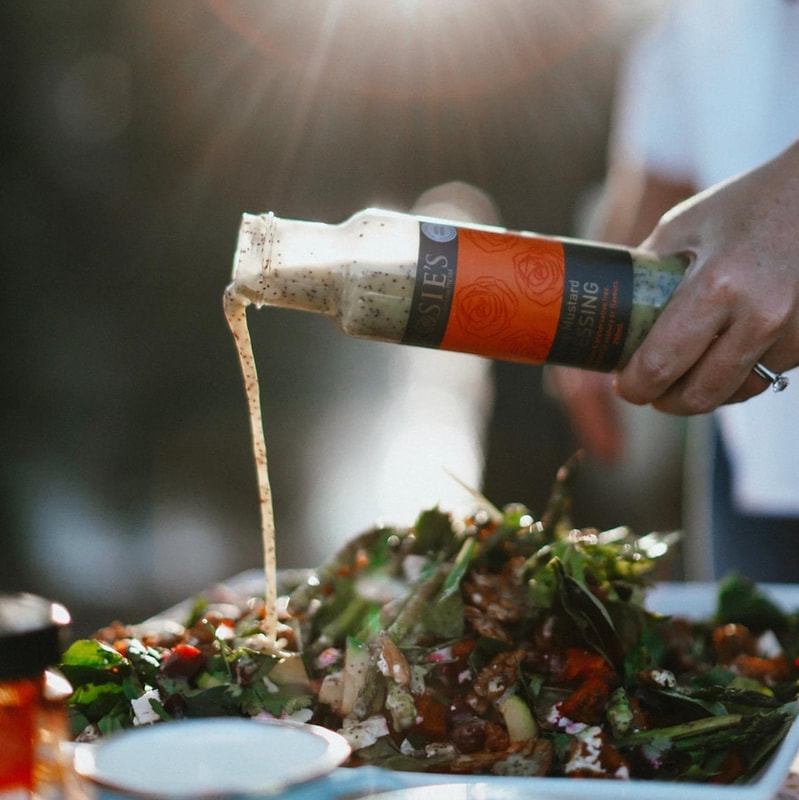 pouring a bottle of poppy seed dressing over a salad