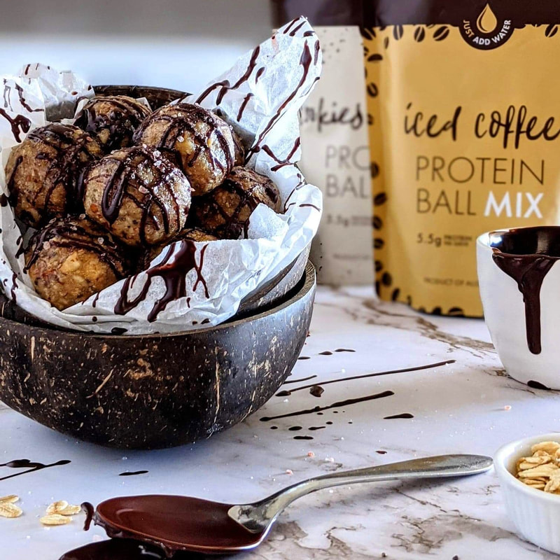 protein balls drizzled with chocolate in a coconut shell bowl